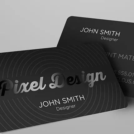 Two dark business cards with a spot-gloss pattern resting on a light grey surface